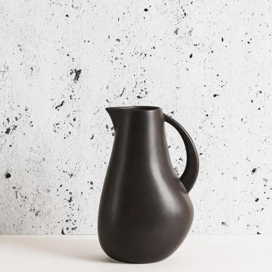 Black stoneware pitcher against a marbled background.