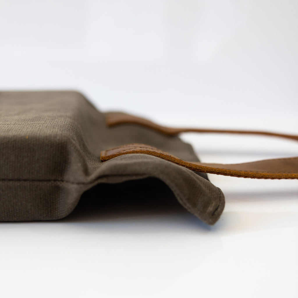 Brown waxed canvas foam kneeler with tan leather handles. Close view of the side and handle from the side.