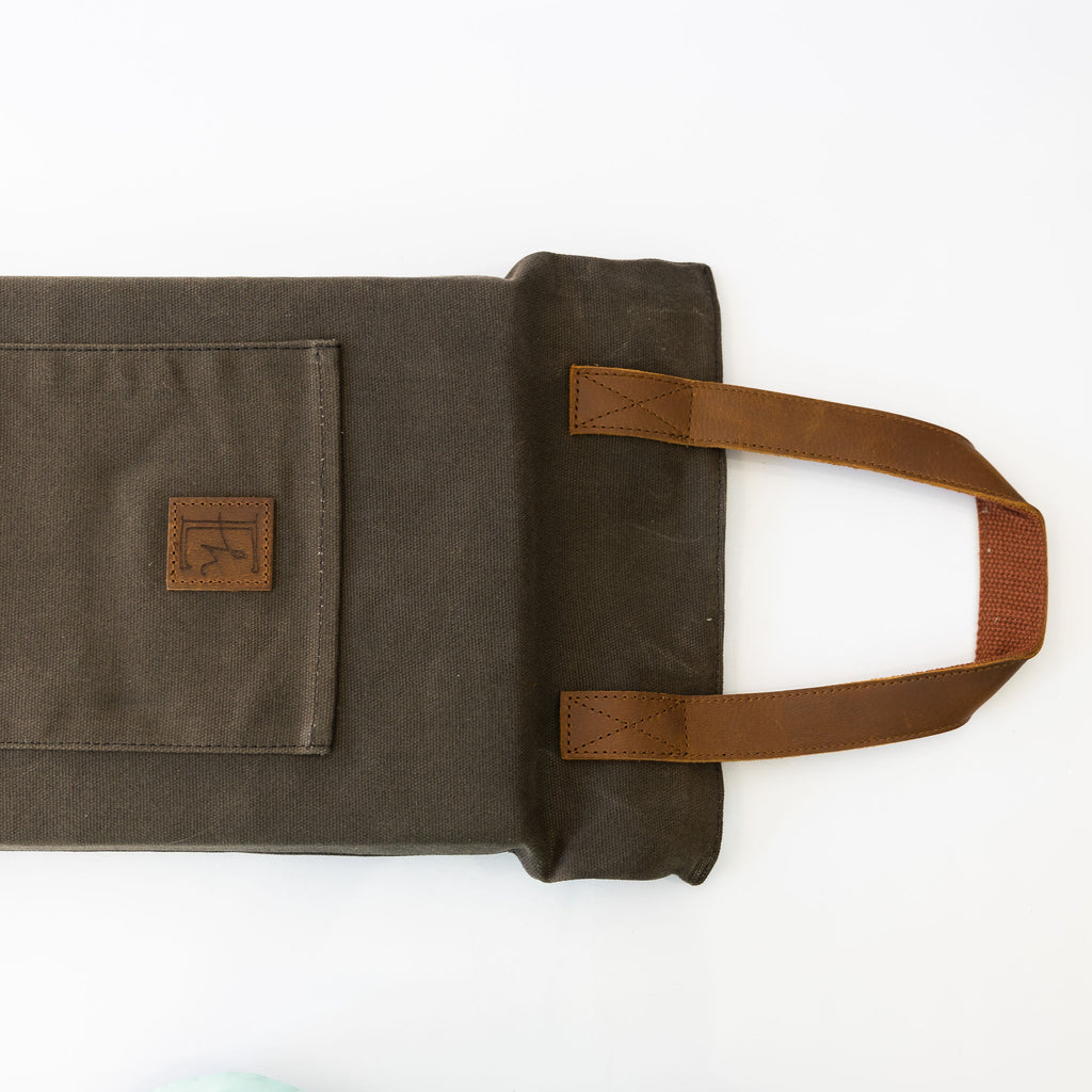 Brown waxed canvas foam kneeler with tan leather handles. Pocket on one side.
