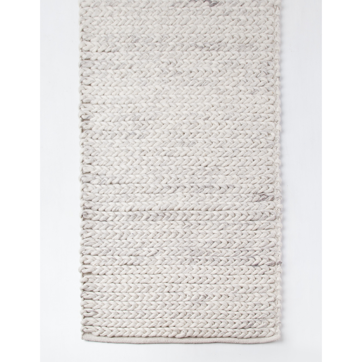Braided natural toned wool knitted rug on white background. 
