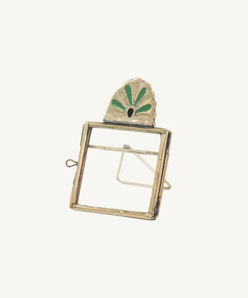 Small brass frame with simple border and a green and brass art deco petal fan on top. White background.