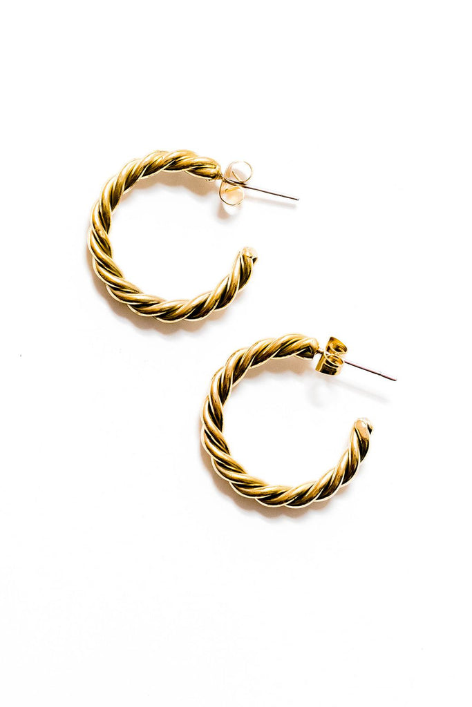 Spiral brass hoops lay on a white background.