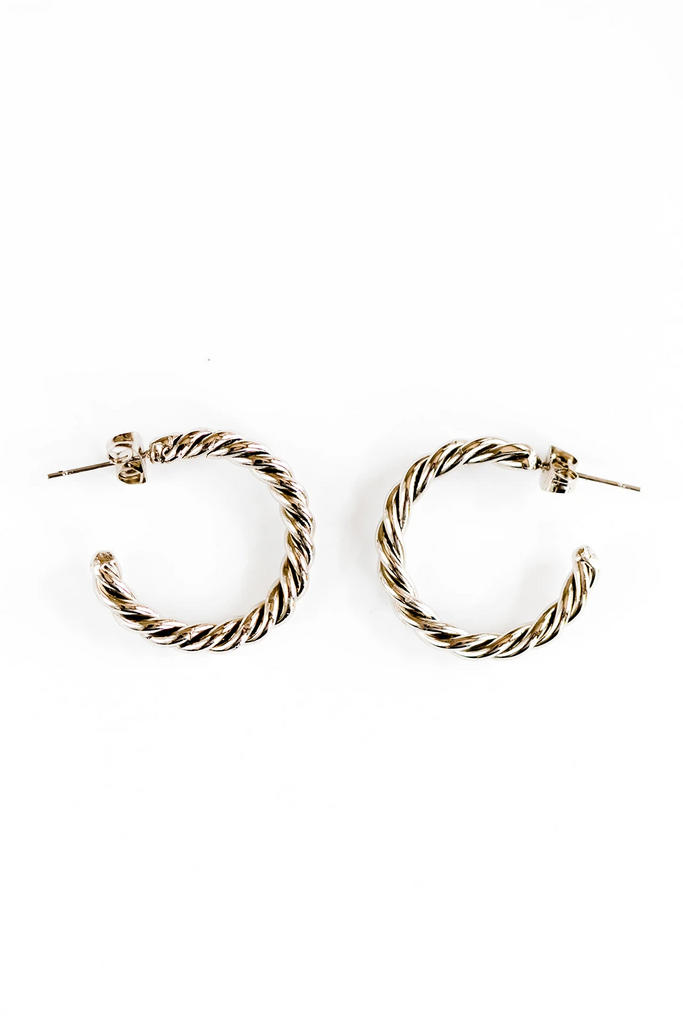 Spiral silver hoops lay on a white background.